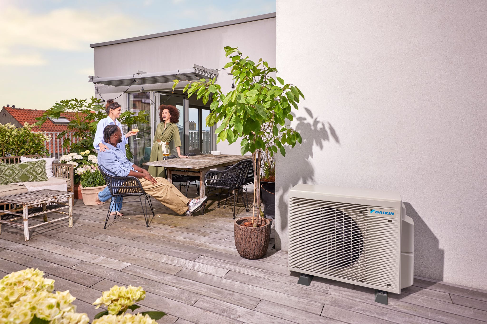 Žmonės ilsisi saulėtoje stogo terasoje visai šalia „Daikin“ multi-split lauko bloko