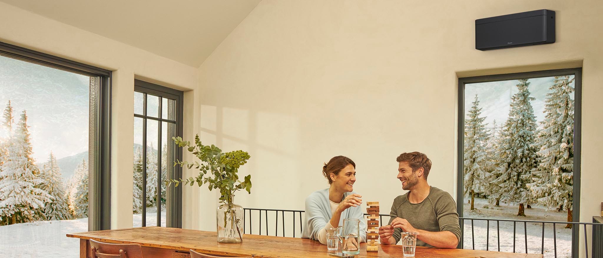 Juodas Daikin NORDIC Stylish FTXTA30CB namelio valgomajame, už langų apsnigtos eglės