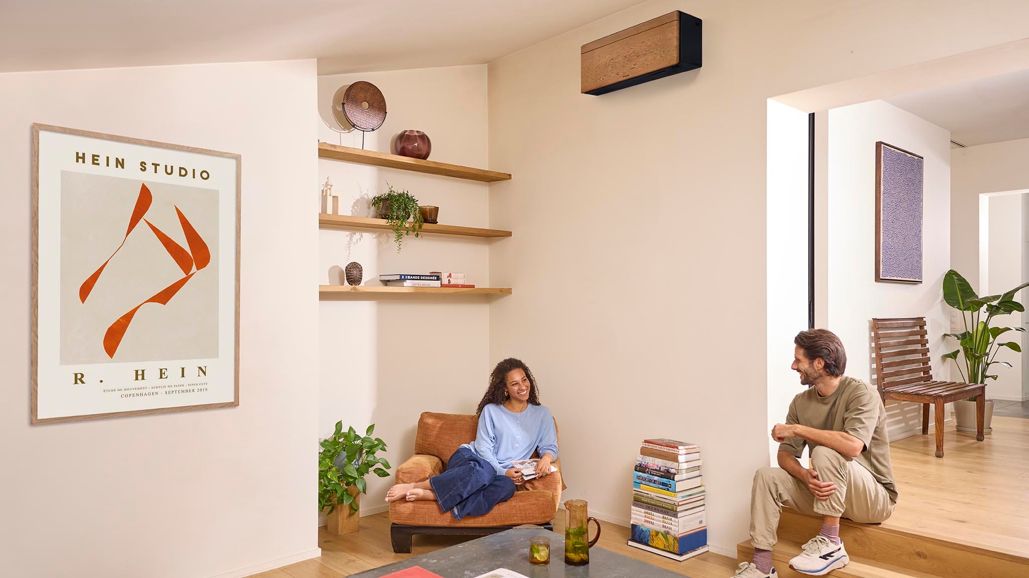 Daikin Stylish FTXA25DY su tamsaus medžio stiliaus skydeliu ir juodu korpusu šviesioje svetainėje