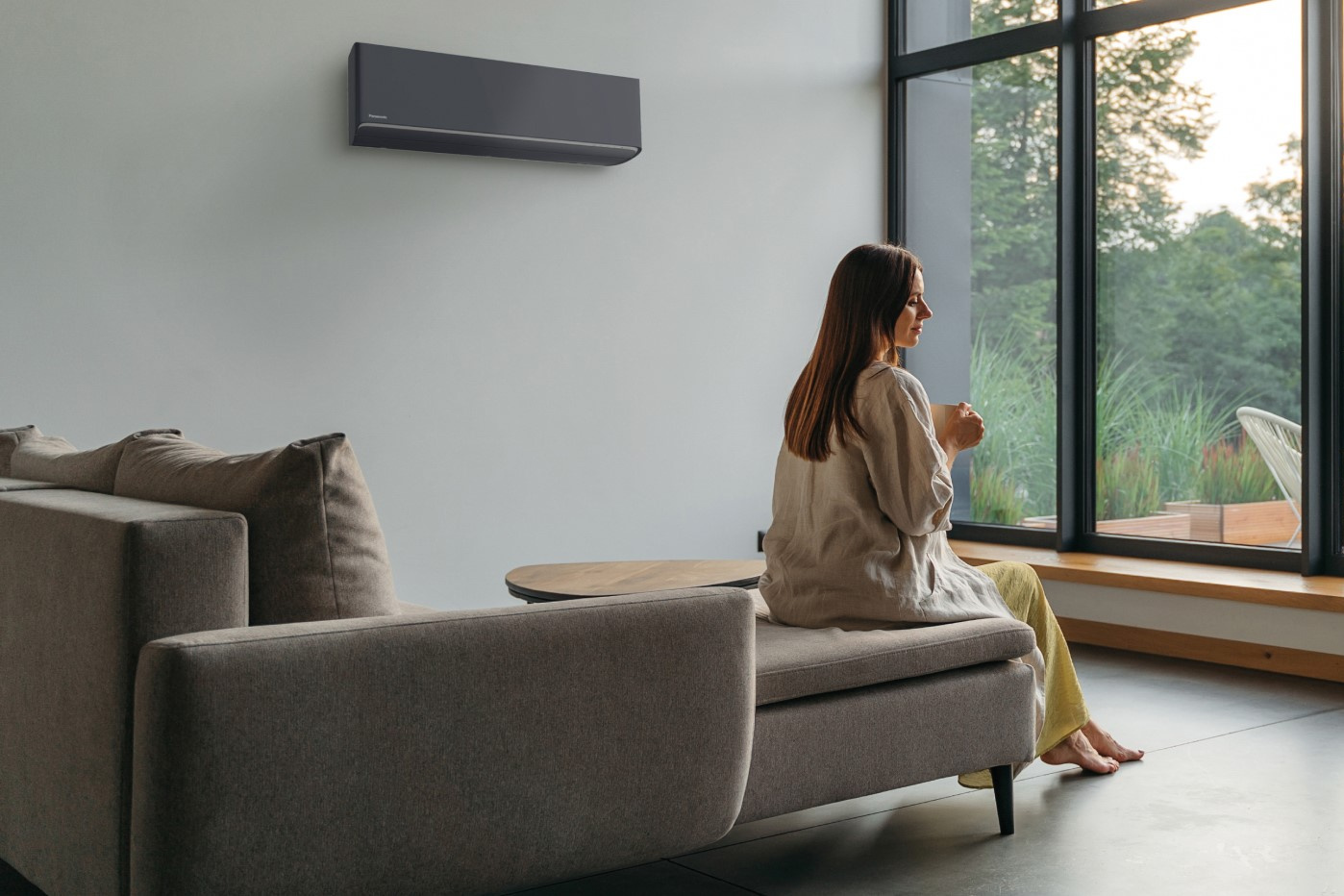 Panasonic Etherea CS-XZ35CKEW-H grafito pilkas šilumos siurblys šviesioje svetainėje su langais į mišką