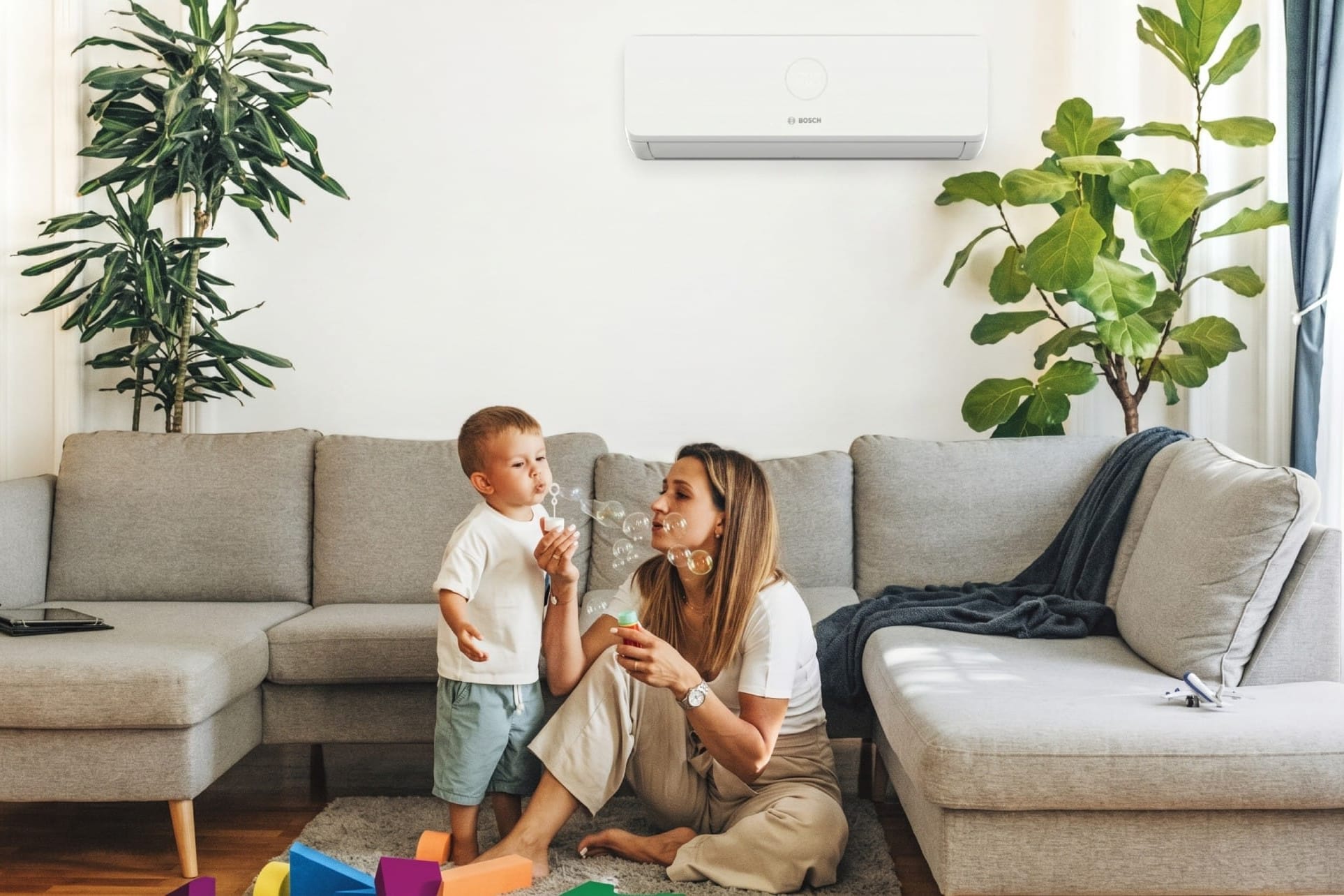 Bosch Climate 5100i CL5100i W 35 HE šilumos siurblys svetainėje – mama su sūnumi pučia muilo burbulus